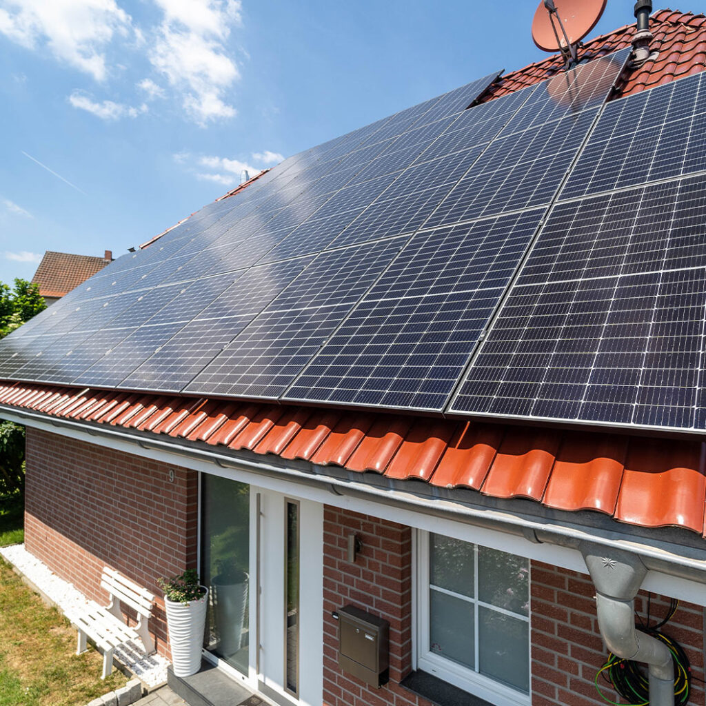 Modern Ziegeldach mit großen blauen Solarpanels und einer Satellitenschüssel