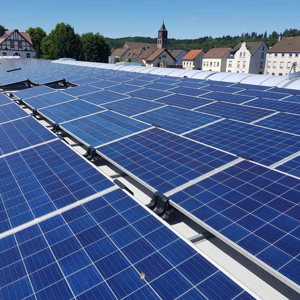 Solarmodule auf einem Dach in einem sonnigen Dorf mit Kirchturm im Hintergrund