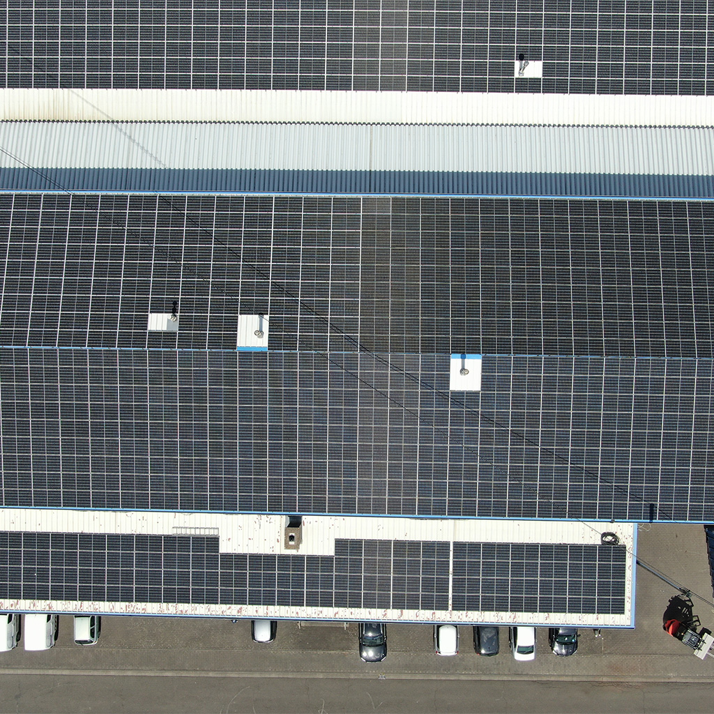 Luftaufnahme eines großen Gebäudes mit dunklen Solarpanels auf dem Dach
