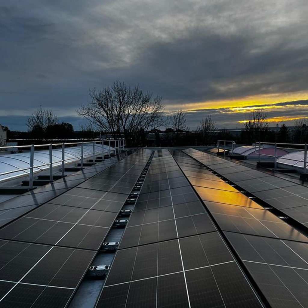 Solarmodule auf einem Dach spiegeln den gelben Sonnenuntergang am wolkigen Himmel