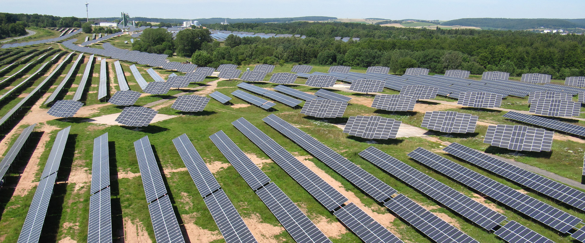 Eine große Solaranlage mit vielen dunkelblauen Solarpanels auf grünem Feld