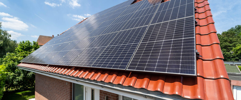 Eine große Solaranlage auf einem roten Ziegeldach bei sonnigem Wetter