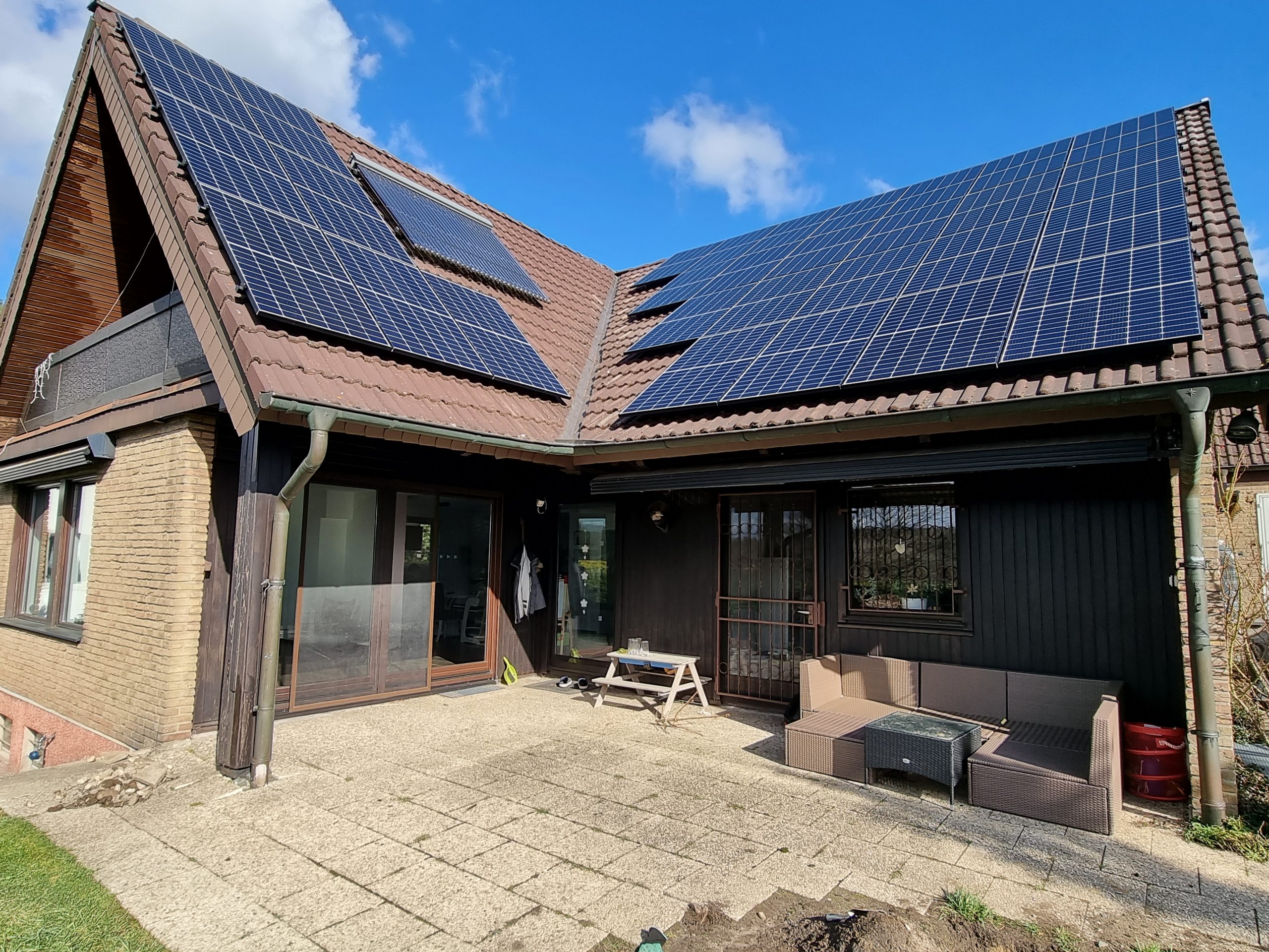 Ein Einfamilienhaus mit braunem Dach und großen Solarpanels bei Sonnenschein