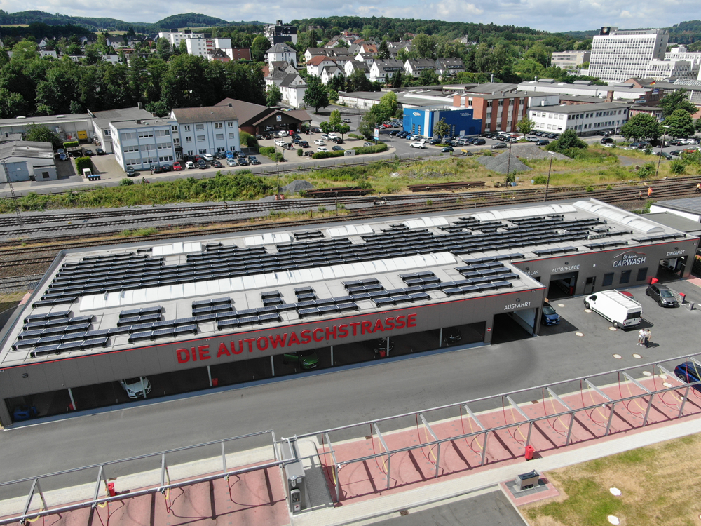 Große Autowaschanlage mit roten Buchstaben auf dem Dach und vielen Solarpanels