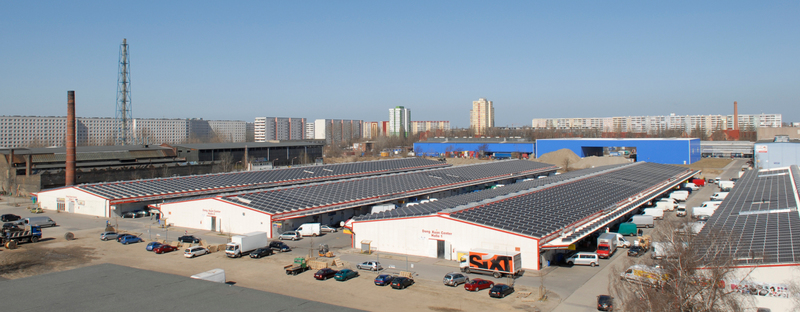 Gewerbegebiet mit weißen Hallen und vielen Solarpanels auf den Dächern im Sonnenschein