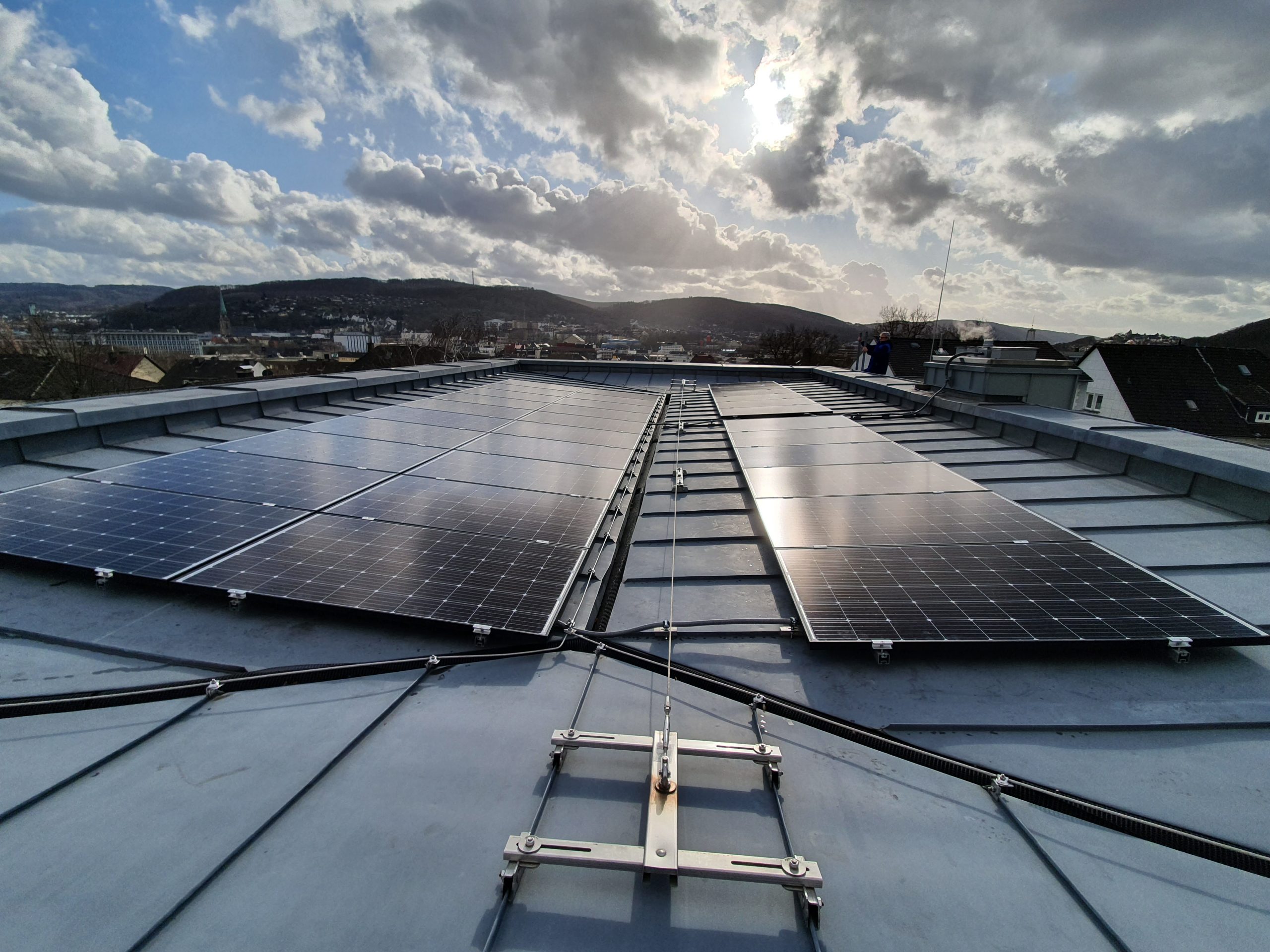 Solarmodule auf einem grauen Metalldach glänzen in der Sonne unter bewölktem Himmel