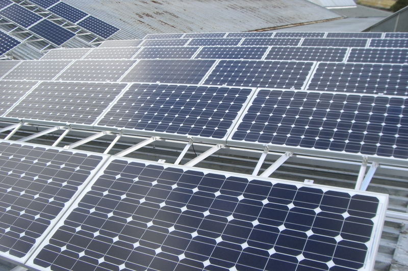Mehrere blaue Solarpanels auf einem silbernen Metalldach bei Tageslicht