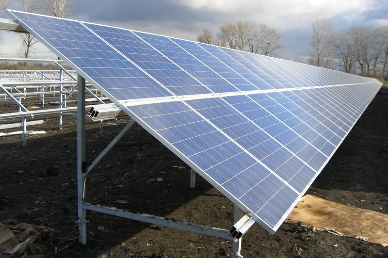Eine große blaue Solaranlage steht draußen auf dunklem Boden unter bewölktem Himmel