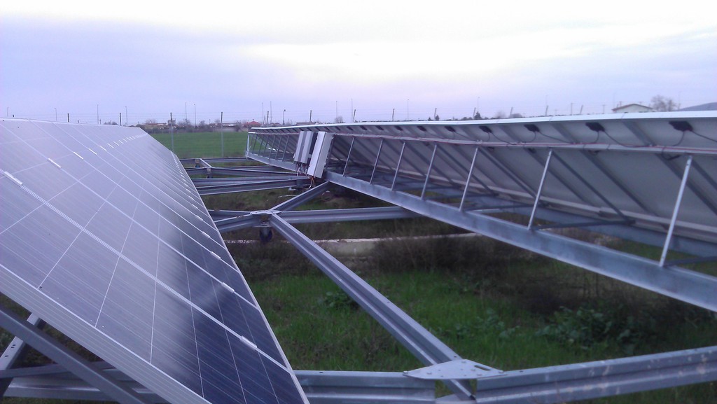 Mehrere große Solarpanels auf Metallgestellen stehen auf grünem Grasfeld im Freien