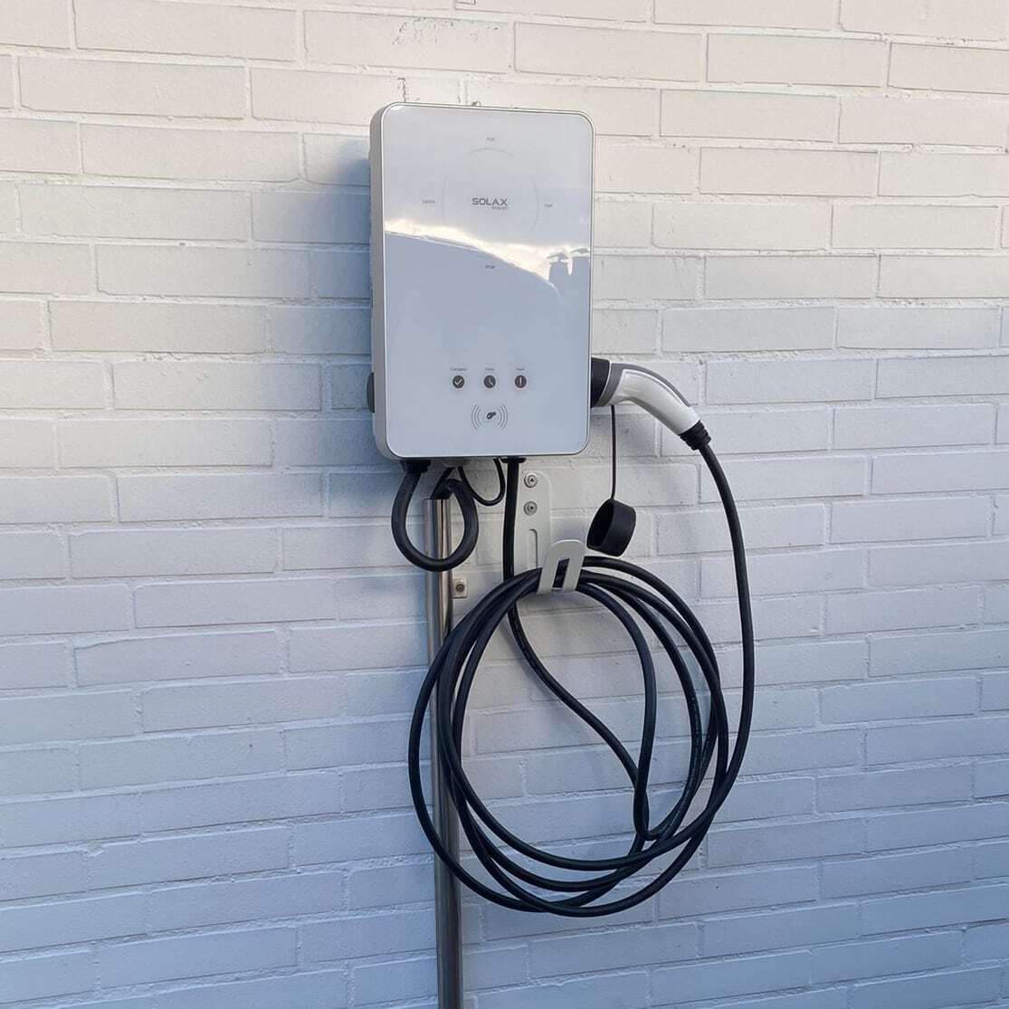 Weiße Solax Wallbox an weißer Wand mit schwarzem Kabel und Stecker