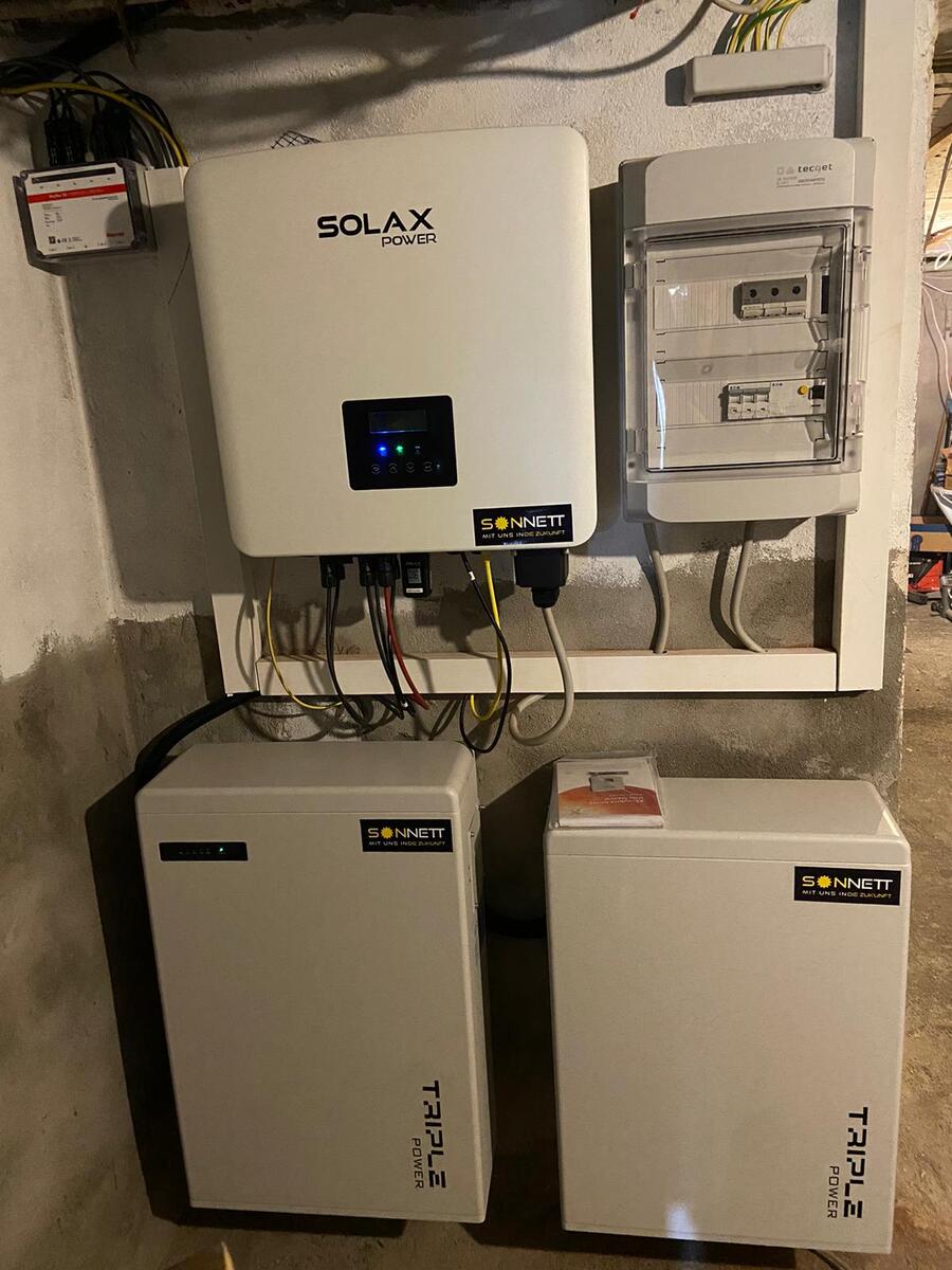 Weiße Solax Anlage mit Kabeln und grüner Anzeige im Technikraum