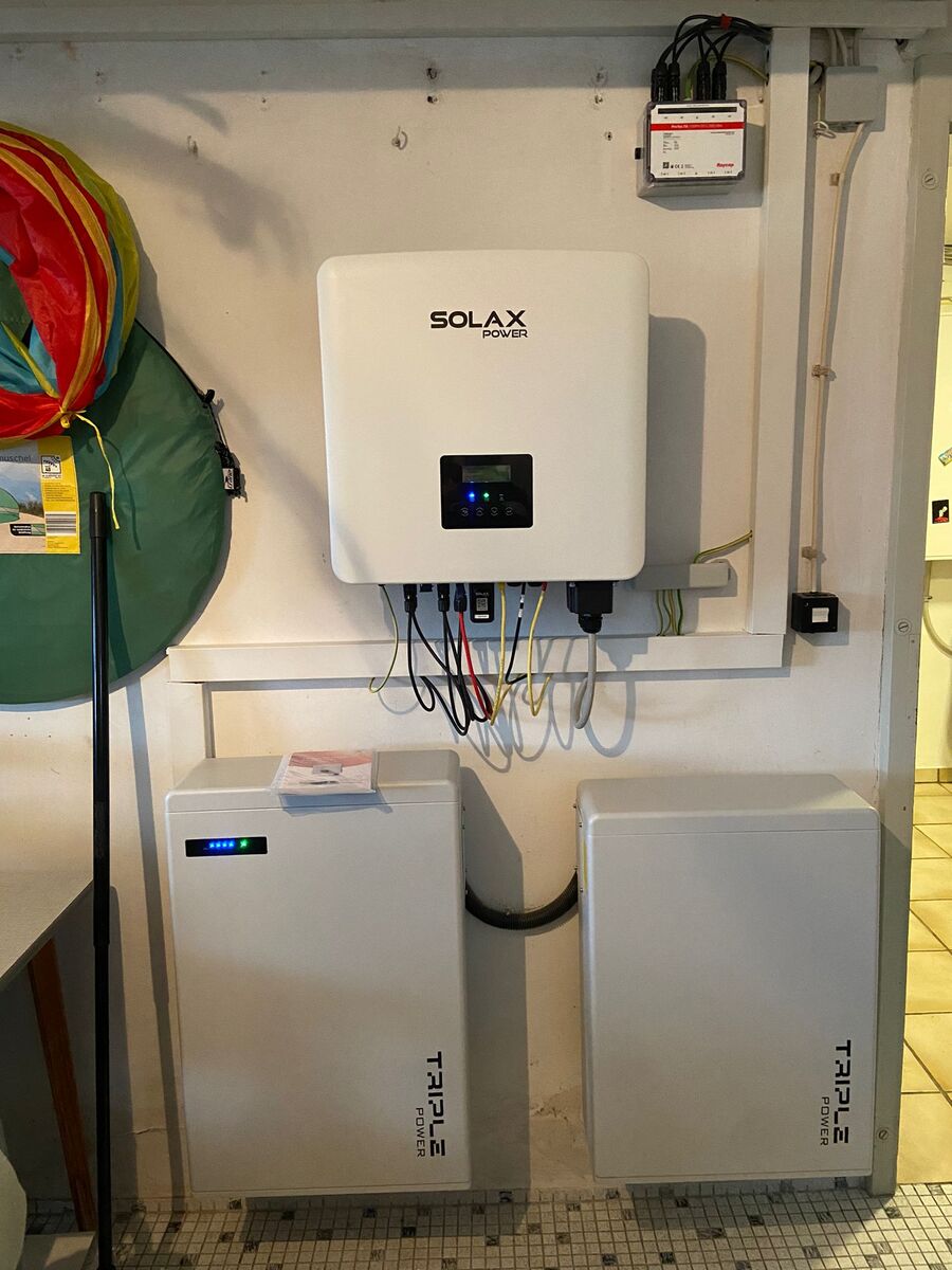 Weiße Solax Power Box mit Kabeln und zwei Tesla Akkus an Wand montiert