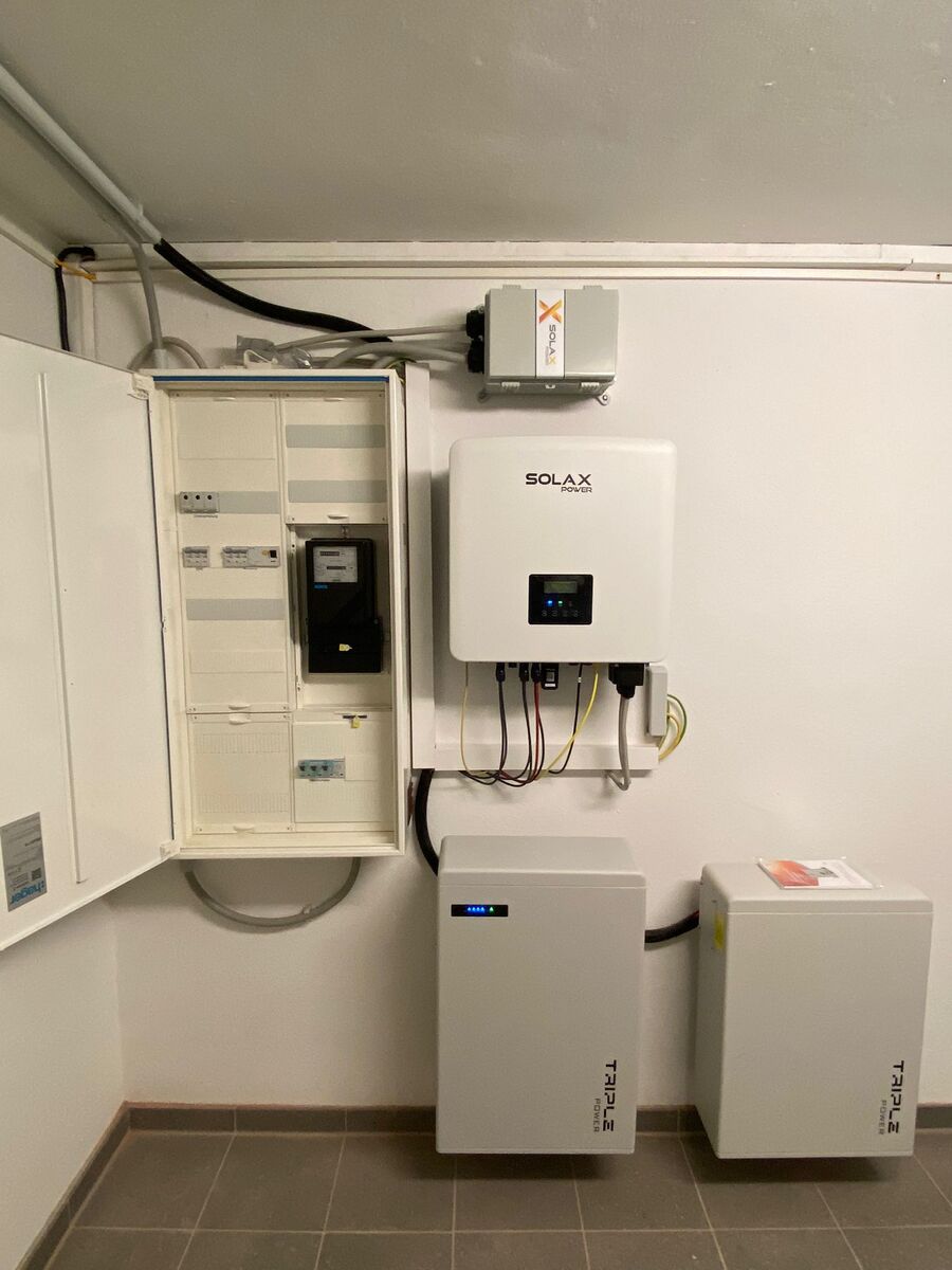 Graue Solax Anlagen an Wand mit offenen Sicherungskasten und Kabeln