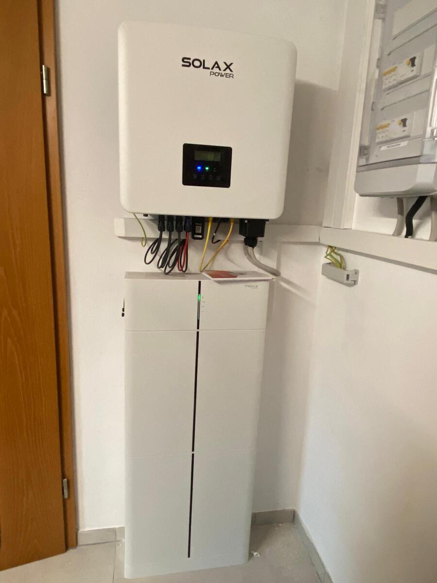 Weißes Solax Power Gerät mit blauem Display und Kabeln über Akkugehäuse
