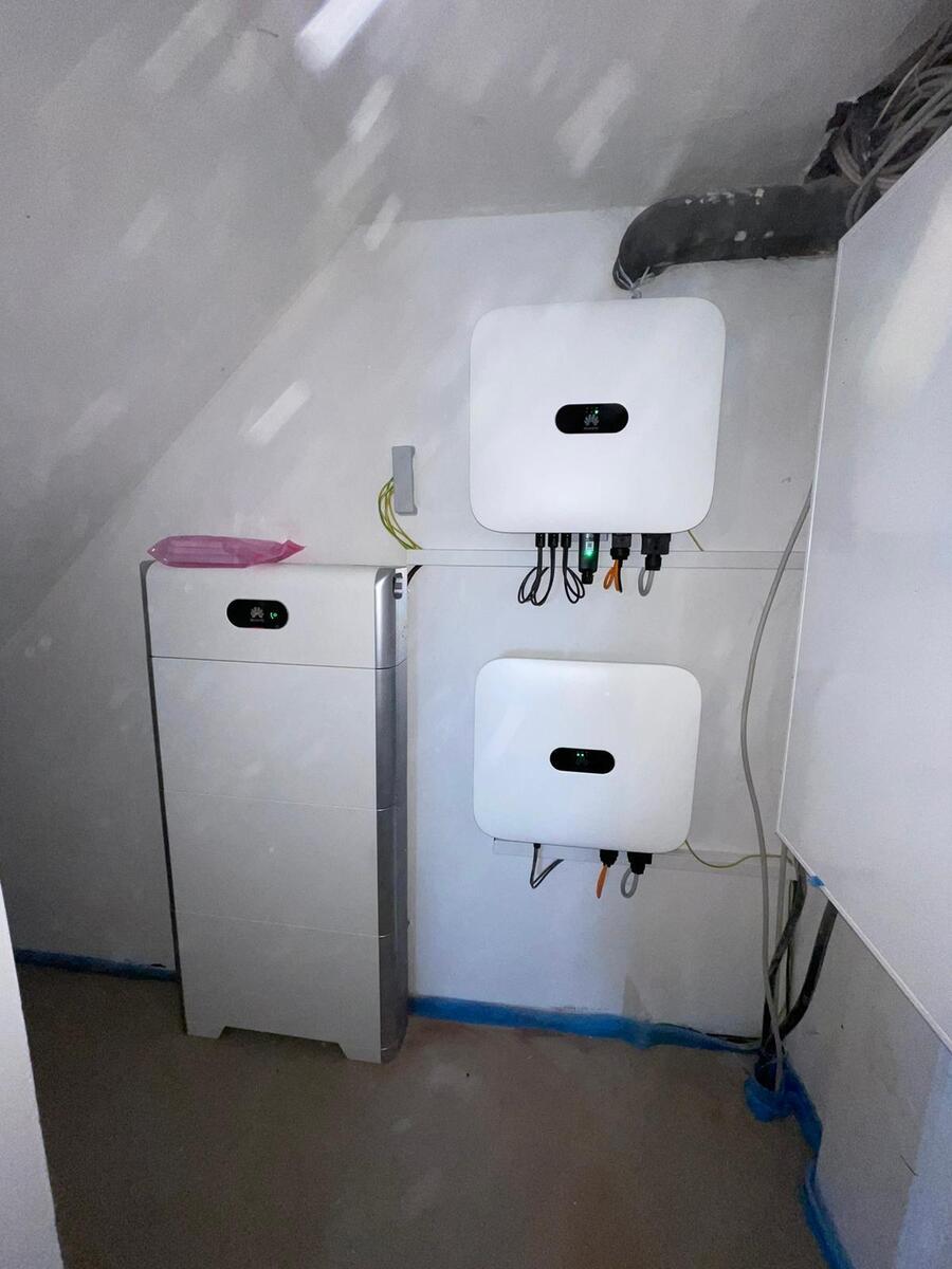 Weiße Technikboxen an Wand, schwarze Kabel, rosa Deckel links, Kellerraum