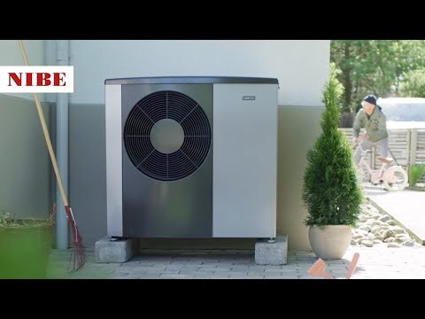 Graue Wärmepumpe mit schwarzem Ventilatorgitter neben Topfpflanze