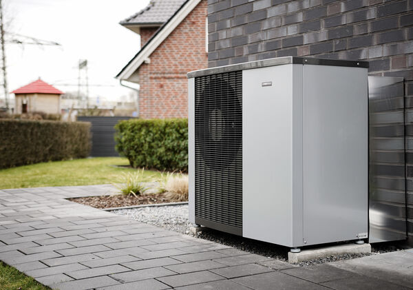 Grau weiße Wärmepumpe mit schwarzem Gitter am Haus, modernes Design
