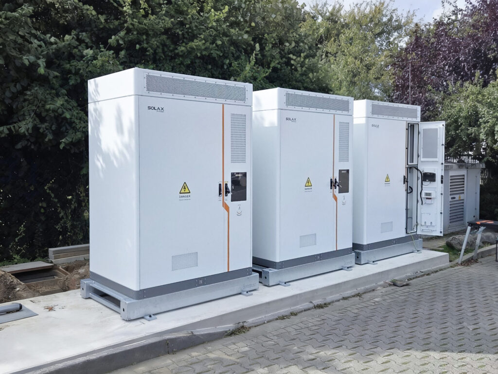 Drei weisse Solax Batteriespeicher stehen im Freien auf einem Betonsockel